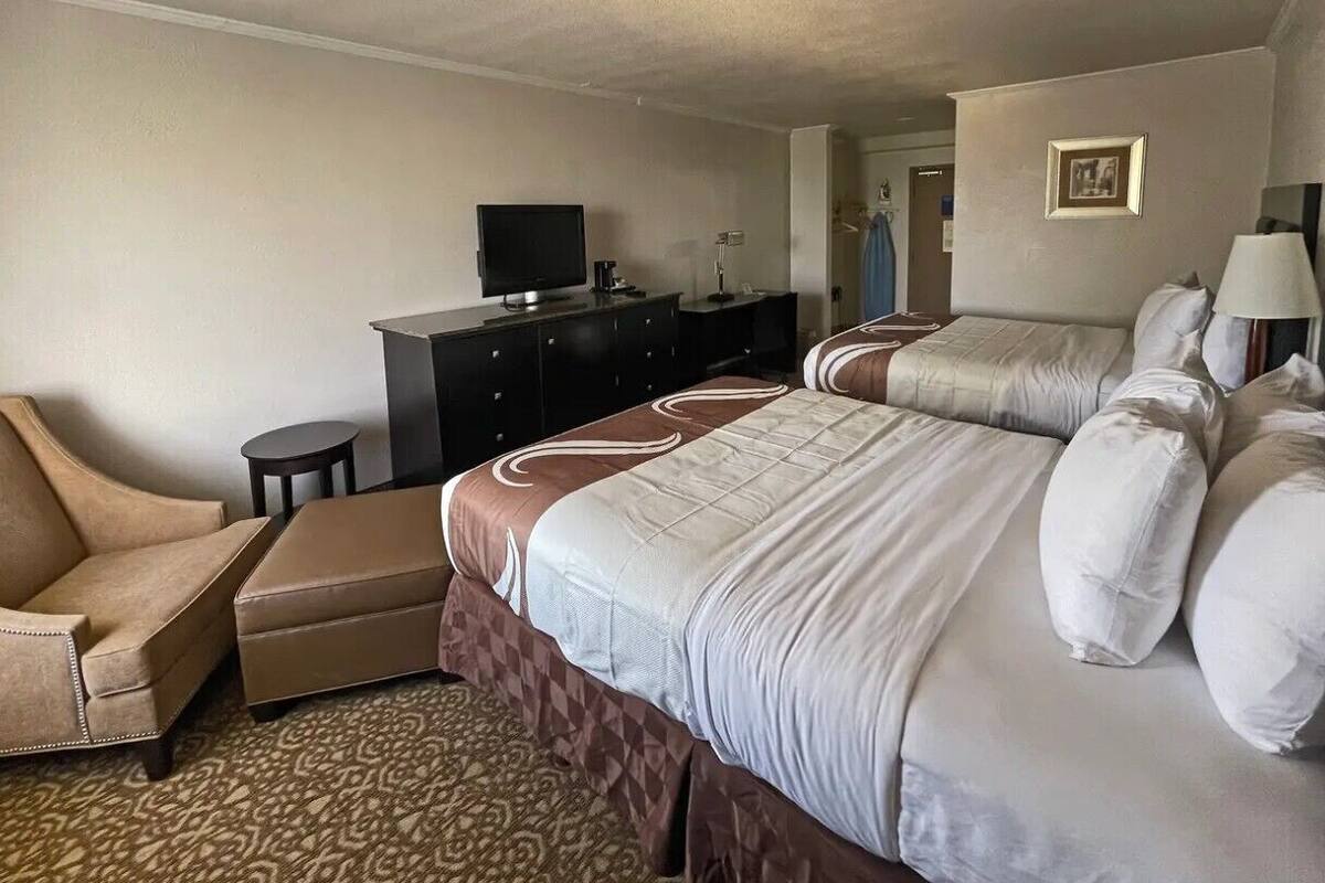 A hotel room with a bed, a sofa, a desk, and a television.