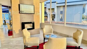 Un salon moderne doté d’un téléviseur à écran plat fixé au mur, d’une cheminée et de sièges confortables, le tout agrémenté d’un tapis rouge.