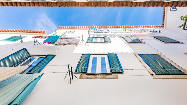 Une terrasse sur le toit dotée de nombreuses fenêtres, dont certaines sont équipées de volets, et de quelques parasols.