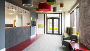 Un interior moderno con mostrador de recepción, zona de estar y ventanas amplias.