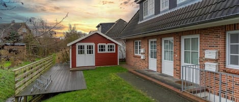A residential property with a red house, a brick house, and a wooden deck.