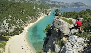 Paisatge costaner amb una platja, penya-segades rocoses i una vista clara del mar.
