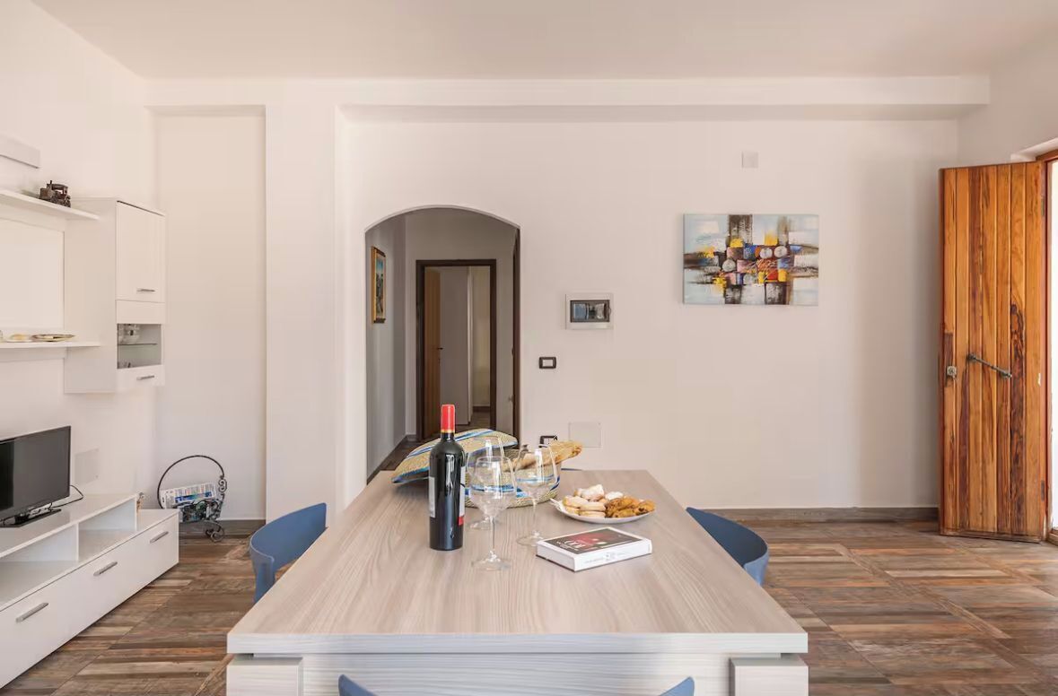 A modern dining area with a wooden table, chairs, a wine bottle, and a plate of food.