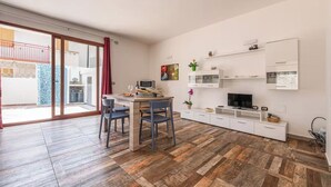 Ein modernes Wohnzimmer mit Essbereich, Fernseher und einem Balkon mit Blick nach außen.
