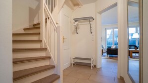 Un escalier menant à une pièce où se trouvent un banc et un porte-serviettes.