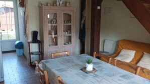 Un comedor con una mesa dispuesta para cuatro, sillas de madera, un armario con puertas de vidrio y un ventilador de techo.