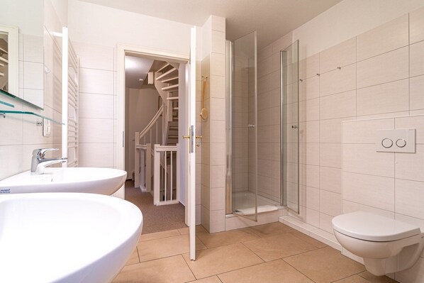 A bathroom with two sinks, a toilet, and a glass-enclosed shower.