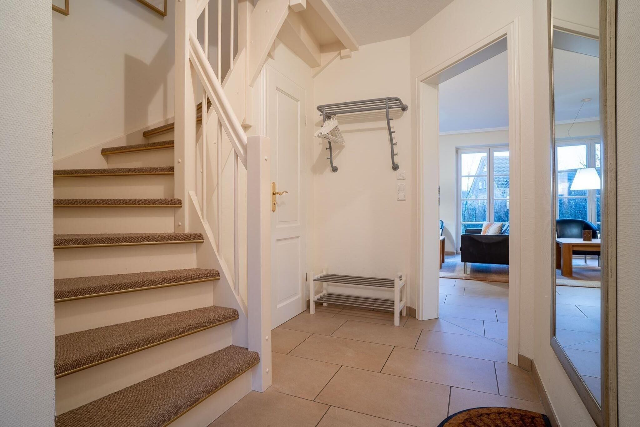 A staircase with carpeted steps leading to a door, a bench, and a radiator.
