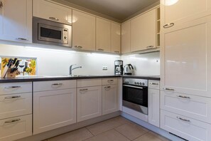 A kitchen with white cabinets, a microwave, a Bosch oven, and a coffee maker.
