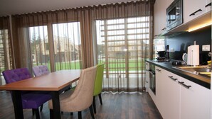 A modern kitchen with a dining area, large windows, and a view of a green outdoor space. - Chalet in Wendorf (Wendorf)