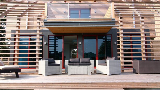 A modern outdoor living area with wicker furniture and a wooden deck. - Chalet in Wendorf (Wendorf)