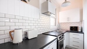 Eine moderne Küche mit weißen Schränken, einer schwarzen Arbeitsplatte, einem Wasserkocher, einem Toaster, einem Herd und einer Mikrowelle.
