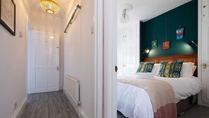 Ein Schlafzimmer mit einem Bett, einem Kopfteil und einer Wand mit Kunstwerken.