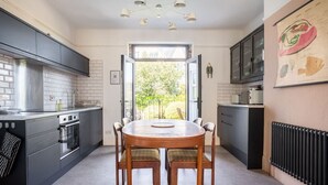 Una cocina moderna con una isla central, armarios negros y una mesa de comedor con sillas.