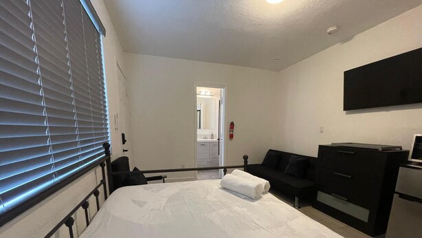 A hotel room with a bed, a black sofa, a dresser, and a television.