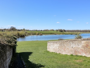 A grassy area with a stone wall and a river.