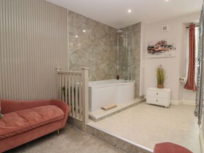 A modern bathroom with a glass-enclosed shower, a white vanity, and a red sofa. - 2 Abbey Row (Kelso)
