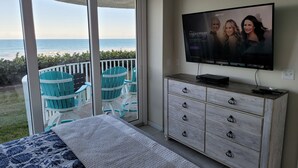 Un dormitorio con balcón, televisión y cama con colcha estampada.