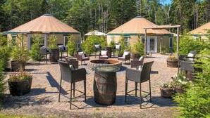Un patio con mobiliario exterior, una fogata y yurtas.