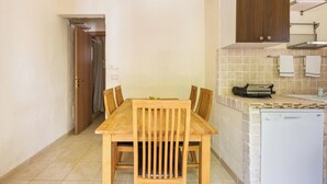 A compact kitchen with a wooden table and chairs, a white dishwasher, and a small countertop with a toaster.