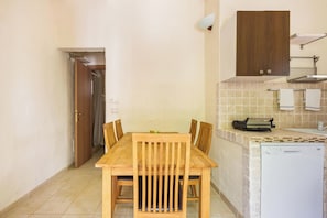 Une cuisine compacte avec une table à manger en bois, un lave-vaisselle blanc et un petit plan de travail sur lequel se trouve un grille-pain.