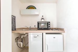 Une petite cuisine équipée comprenant un lave-vaisselle intégré, un petit réfrigérateur et un four grille-pain.