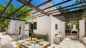 An outdoor patio with a table set for dining, surrounded by colorful chairs.