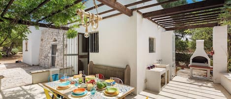 Une terrasse extérieure avec une table dressée pour le repas, entourée de chaises aux couleurs vives.