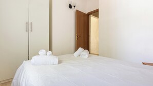 A hotel room with a bed, a wardrobe, and a door leading to another room.