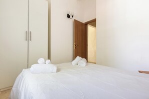 A hotel room with a bed, a wardrobe, and a door leading to another room.