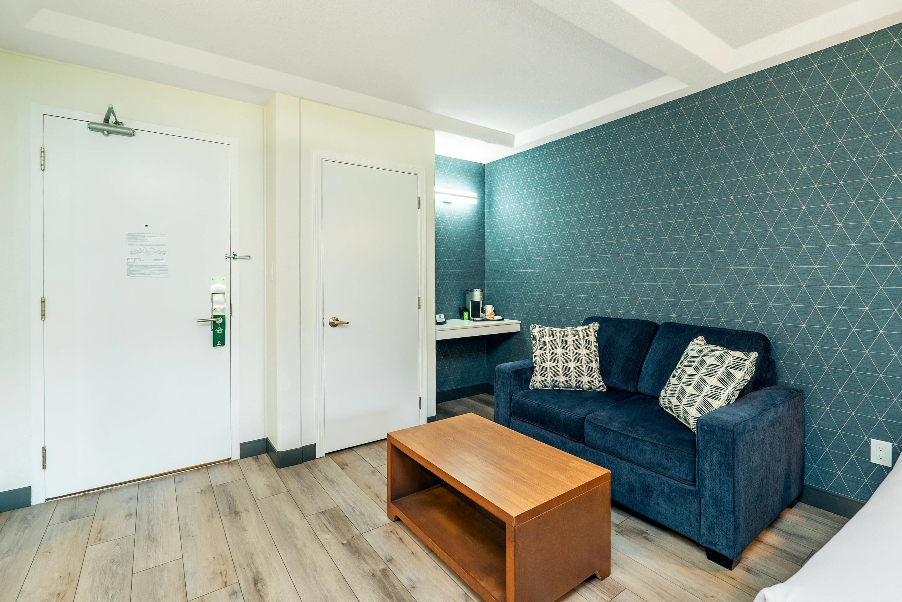 A room with a blue sofa, a wooden coffee table, and a white door with a green handle.
