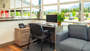 A modern office with a desk, chair, and computer, large windows with a view of a parking lot and mountains. - Quality Inn & Suites (Clearwater)