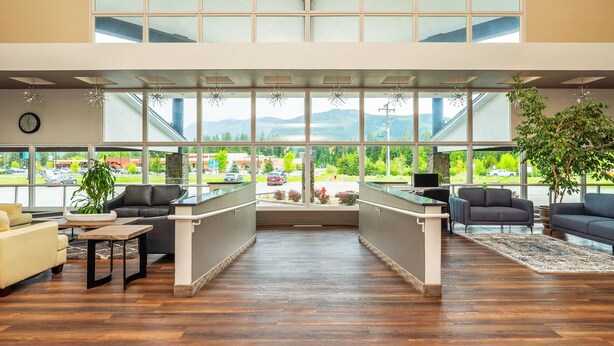 A spacious lobby with a high ceiling, large windows offering a view of the outdoors, and a seating area with sofas and a coffee table. - Quality Inn & Suites (Clearwater)