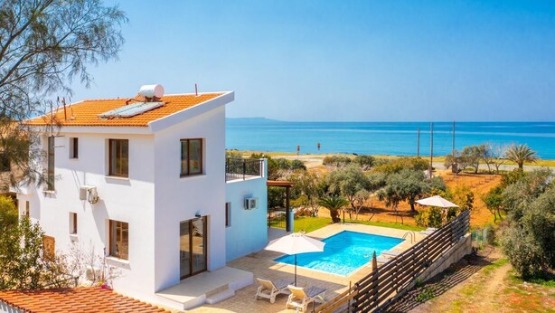 Una villa moderna de color blanco con piscina en la azotea, un balcón y vistas al mar.