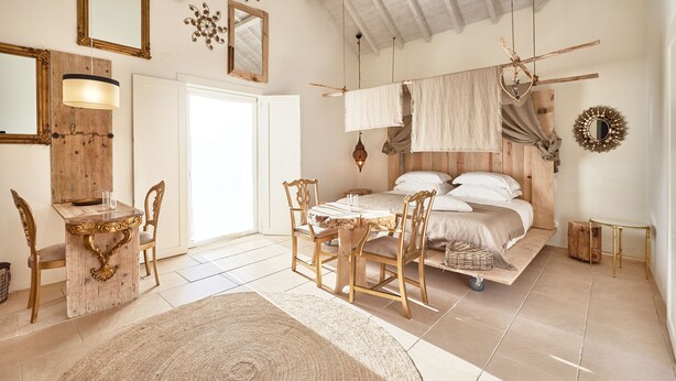 Una habitación con cama, muebles de madera, una mesa de comedor y un candelabro.