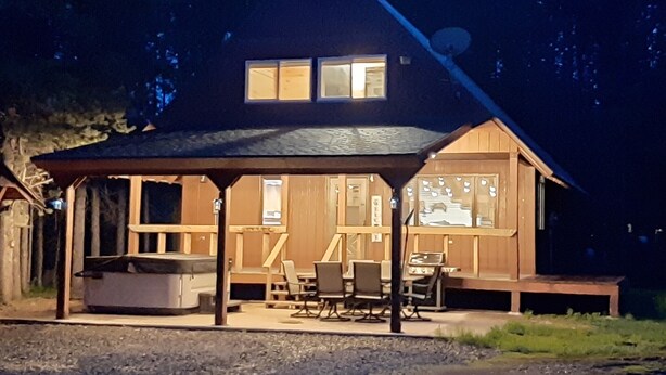 A wooden cabin with a covered porch, a fireplace, and a dining area. - Family Adventure Cabin/Near Yellowstone/Hot Tub (Island Park)