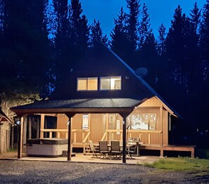 Une cabane en bois dotée d’un porche abrité, d’une cheminée et d’un coin repas.