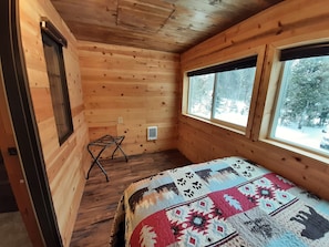 Une pièce de cabane en bois comprenant un lit, une fenêtre et un radiateur.