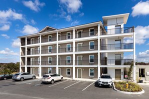Un hôtel à plusieurs étages, doté d’un parking et surplombant un ciel d’un bleu limpide.