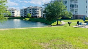 A residential area with a lake, a tree-lined pathway, and multi-story buildings with balconies. - Astonishing view great condo at Myrtlewood Villas (Myrtle Beach)