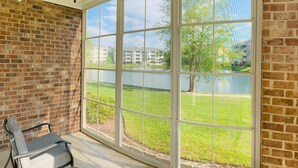 A room with a large window, a brick wall, and a ceiling fan. - Astonishing view great condo at Myrtlewood Villas (Myrtle Beach)