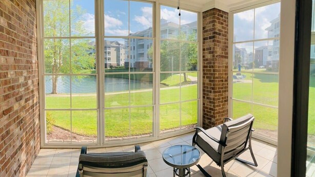 A room with large windows, a brick wall, and two chairs. - Astonishing view great condo at Myrtlewood Villas (Myrtle Beach)