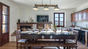 Un comedor con una mesa de madera dispuesta para una comida, una chimenea y un televisor sobre ella.
