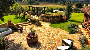 Une terrasse en pierre avec des sièges d’extérieur, un foyer et une pergola.