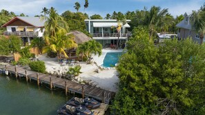 Une propriété située en bord de mer, dotée d’une piscine, d’un quai pour bateaux et d’une structure à toit de chaume.