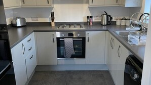 A modern kitchen with grey cabinets, a gas stove, an oven, and a dishwasher.