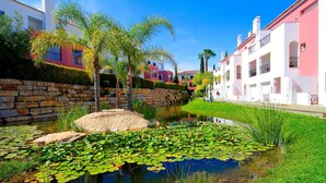 A serene waterway with lily pads, a stone wall, and buildings with balconies.