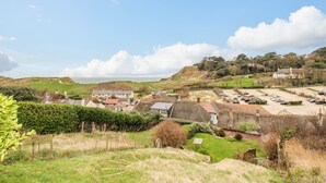 A coastal village with traditional houses, a parking area, and a view of the sea. - Cajun Cottage (Wareham)