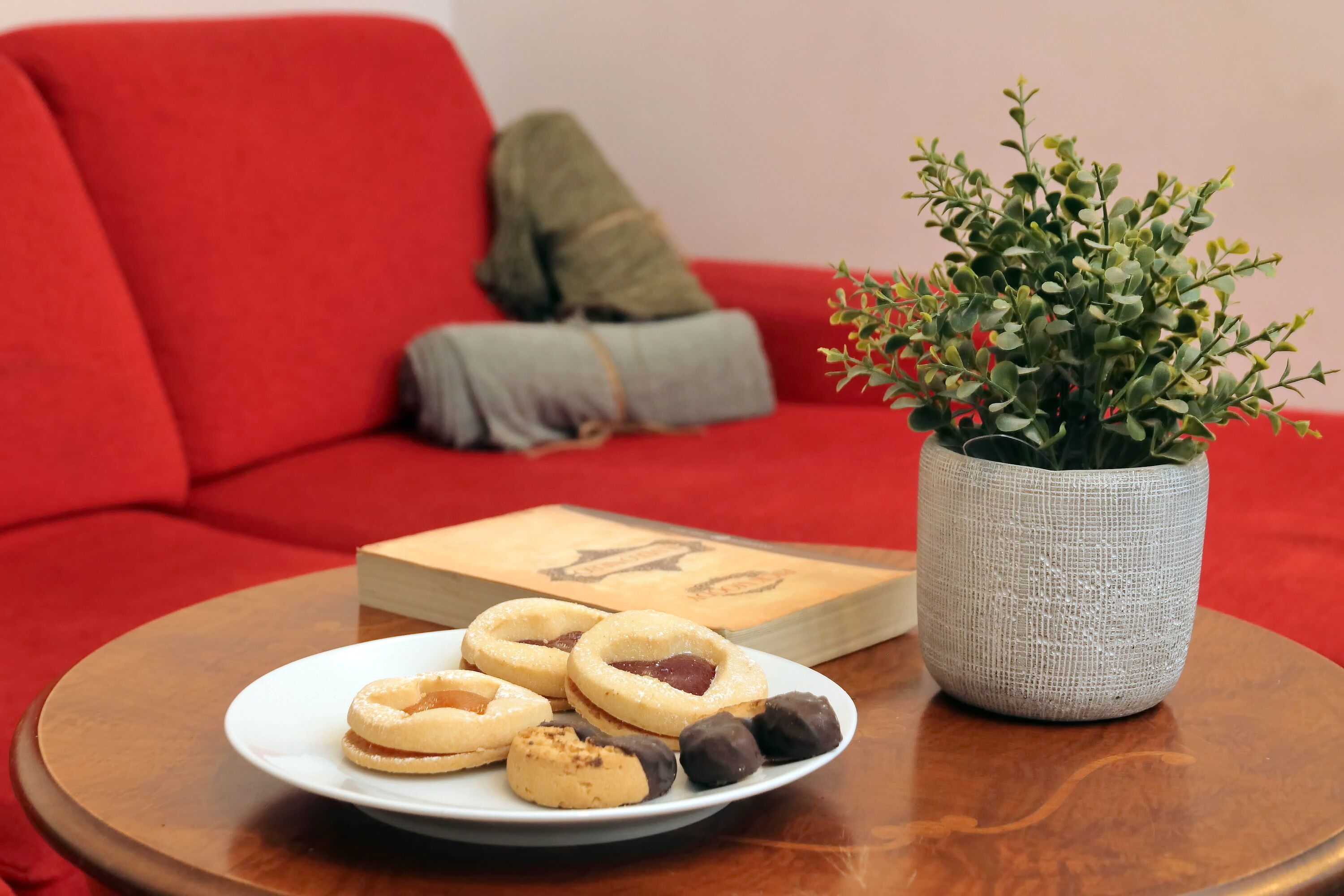 Una mesa redonda de madera con un plato de galletas y una planta en maceta.