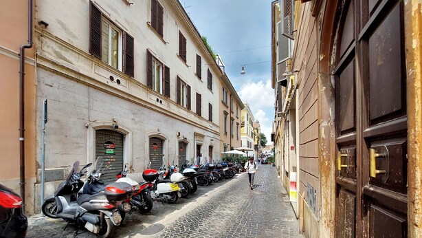 Una calle adoquinada flanqueada por motocicletas estacionadas y edificios históricos con arcos.